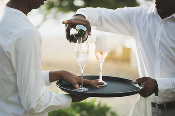 Waiter pouring champagne into glass.