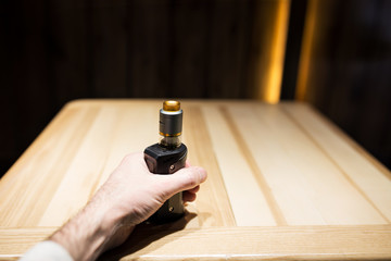 A man's hand holds vape in a cafe, safe smoking