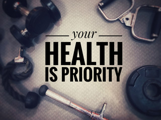Motivational and inspirational fitness concept - Your health is priority with gym equipment as background. Blurred vintage style.