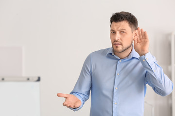 Mature man with hearing problem on blurred background