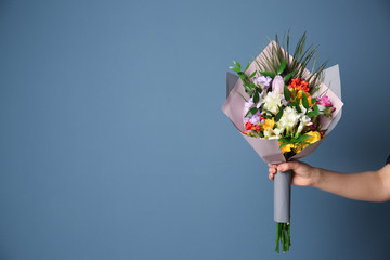 Woman with beautiful bouquet of freesia flowers on color background