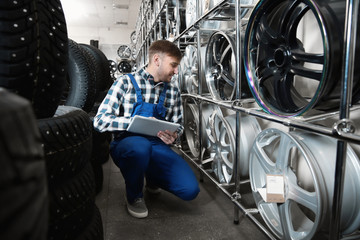 Wall Mural - Young male mechanic with tablet computer in automobile service center