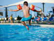 Caucasian boy having fun jumping into the pool.