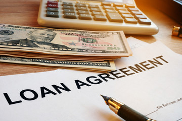 Loan agreement, money and calculator on a desk.