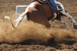 A barrel racing horse slides around the barrel kicking up dirt and dust.
