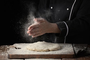 Woman chef hand clap with splash of white flour on a black background