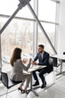 © Seventyfour - Full length portrait of two business people, man and woman, drinking coffee at table in cafe sitting at big window, copy space