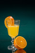 Orangescheibe am Glas mit Orangensaft und halber Orange vertikal