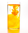 Orange food coloring diffuse in water inside cylinder glass with empty copyspace area for slogan or advertising text message, over isolated white background.