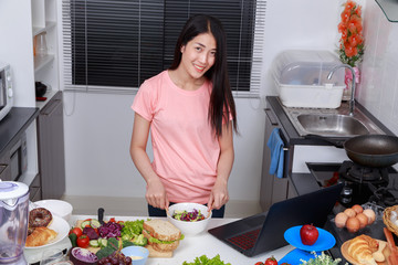 Sticker - woman mixing salad while cooking with laptop in kitchen