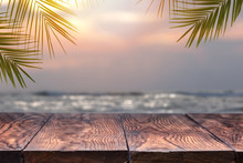 Empty Wooden Table And Palm Leafs On A Background Of Beach Blurred.