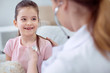© zinkevych - Chronicle ill. Optimistic pleasant girl smiling and looking at female doctor who using stethoscope