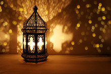 Ornamental Arabic Lantern With Burning Candle Glowing At Night And Glittering Golden Bokeh Lights. Festive Greeting Card, Invitation For Muslim Holy Month Ramadan Kareem. Dark Background.