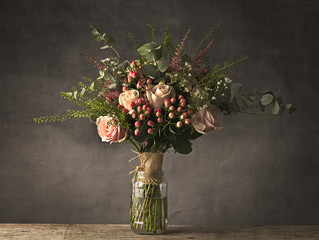 Bouquet of pink roses in a jam jar on a wooden table