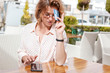 Young attractive girl in glasses with a credit card and a phone in a street cafe, online shopping, payments, bank offers