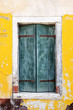 Old wooden window and yellow wall of a house in Burano island near Venice, Italy