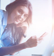 Young woman sitting at the desk with instruments, plan and laptop