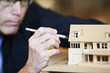 © Mint Images - Caucasian male architect working on a scale model of a new home.