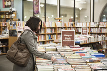 Caucasian female browsing through books in a bookstore.