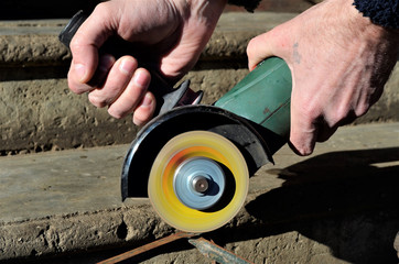 Craftsman sawing metal with disk grinder in workshop