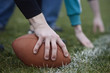 © Mint Images - Close up of a hand holding an oval football on the line, during a game of non-contact flag football.