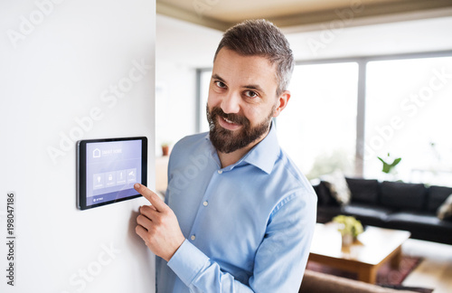 Fotomural A man pointing to a tablet with smart home screen.