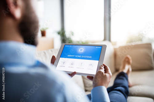 Cuadros en Lienzo A man holding a tablet with smart home screen.