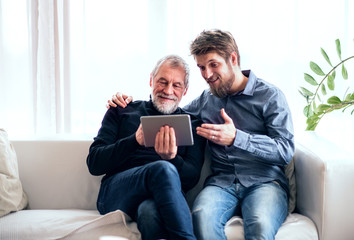 Wall Mural - Hipster son and his senior father with tablet at home.