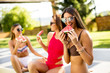© BGStock72 - Young women in swimsuit eating watermelon by pool