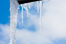 Beautiful Icicles On Edge Of An Roof With Blue Sky On Background. Warm And Melting In Sprin Season