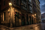 Fototapeta Uliczki - Narrow street corner with warm old lamp in the old city in Bilbao. Spain