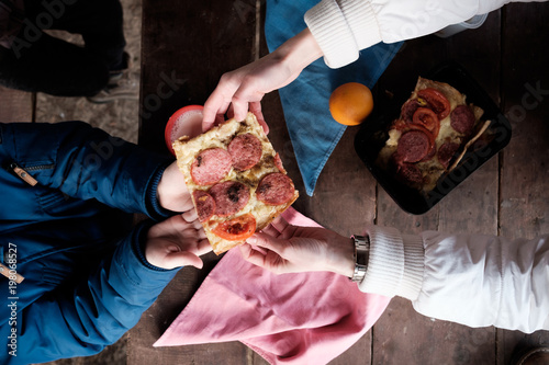 Plakat Ręka matka daje plasterkowi domowej roboty pizza jej syn na wiosna pinkinie. Widok z góry.