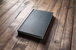 Blank black hardcover book on vintage wood table background.