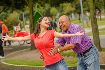 Outdoor view of daughter and father playing at outdoors in the park holding her waist