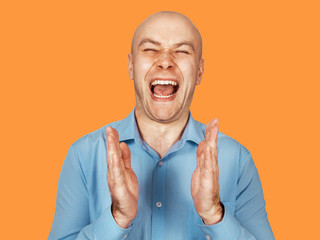 Portrait of a young bald joyful clapping hands guy with a smile. Isolated on orange.