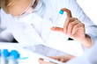© rogerphoto - Closeup of scientific research team with clear solution in laboratory. Blonde female chemist holds test tube of glass while her colleague checks results with tablet pc. Blood test, medicine or