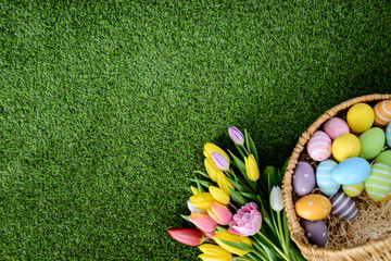 Wall Mural - above top view of multi colored painted easter eggs with springtime tulip bouquet flowers on green grass