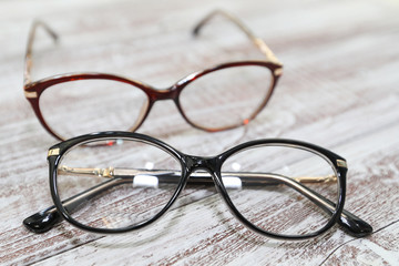 Two pairs of stylish women's eyeglass frames on white wooden background