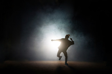 dancing pose of male on one leg on the dark background. being fond of dancing. dancing movements