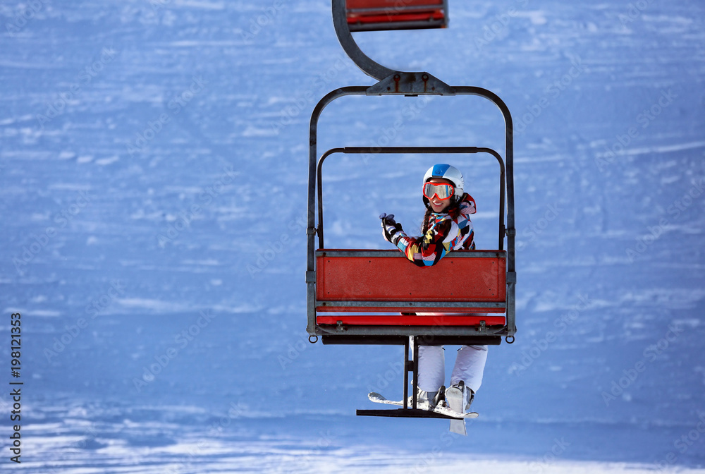 Woman on ski lift at snowy resort. Winter vacation