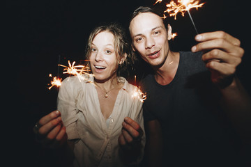 Wall Mural - Caucasian man and woman couple playing with sparklers celebration