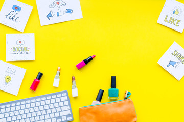 Poster - Female blogger concept. Work desk with keyboard, cosmetics and social media icons on yellow desk top view space for text