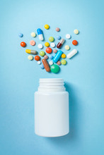 Assorted Pharmaceutical Medicine Pills, Tablets And Capsules And Bottle On Blue Background