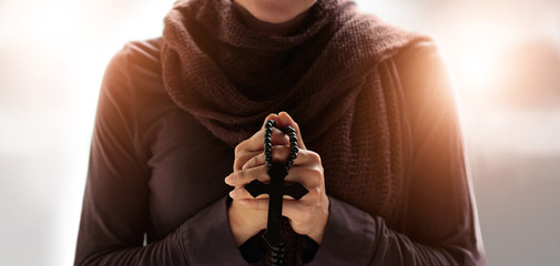 Canvas Print - Christian Religion concept. Woman hands praying with rosary and wooden cross on soft background.