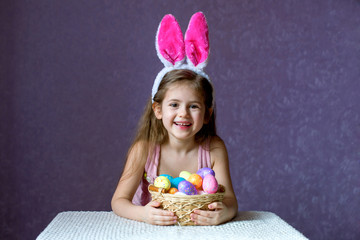 Wall Mural - A girl in a rim with rabbit ears plays with dyed eggs and laughs