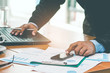 © chaiya - A businessman analyzing investment charts at his workplace and using his laptop ,stock chart , cellphone, close up vintage style.