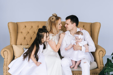 Smiling young parents and their two children are very happy, they are at home on the home interior