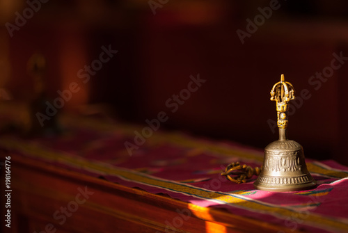 Fotografía Ritual hand bell in the Buddhist temple as the enlightenment symbol, has got to a sunlight beam