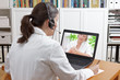 Doctor with headset and laptop, taking notes during an online call with a patient showing a large mole, teledermatology concept.