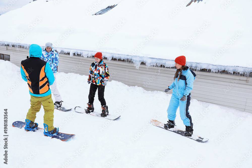 Group of friends taking snowboard lessons at snowy resort. Winter vacation